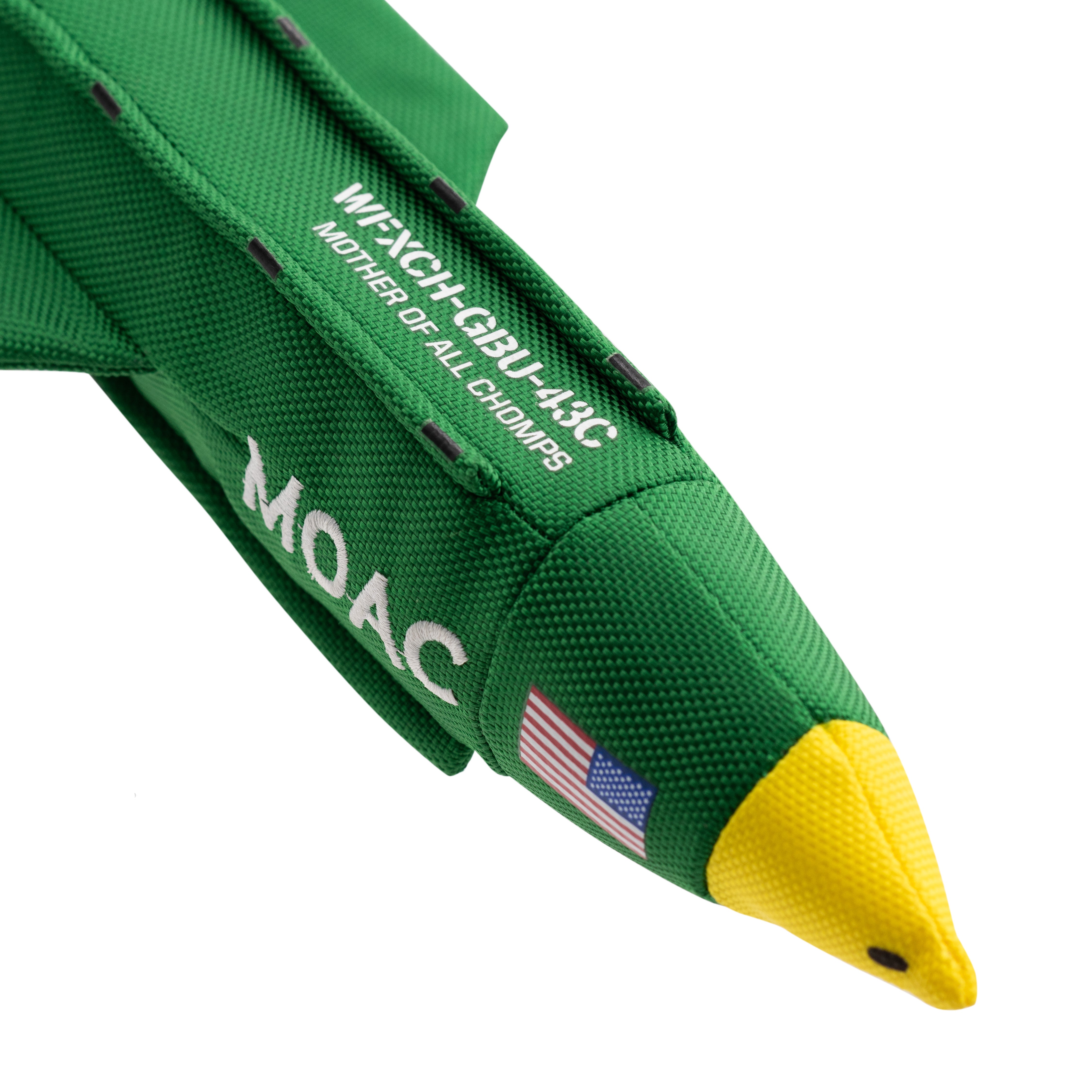 close up image of the Carbon Hound MOAC dog toy nose cone area which is a scale replica of the MOAB military bomb, standing upright on its base. the toy is green, yellow and white with the word MOAC embroidered on the side, with an American flag
