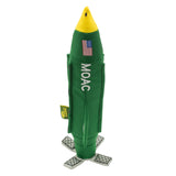 an image of the Carbon Hound MOAC dog toy which is a scale replica of the MOAB military bomb, standing upright on its base. the toy is green, yellow and white with the word MOAC embroidered on the side, with an American flag on the nose cone