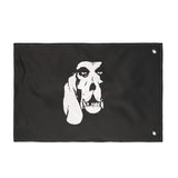 A black rectangular morale flag with two metal grommets on the left side with Carbon Hound's white dog logo in the center, the back side of the flag